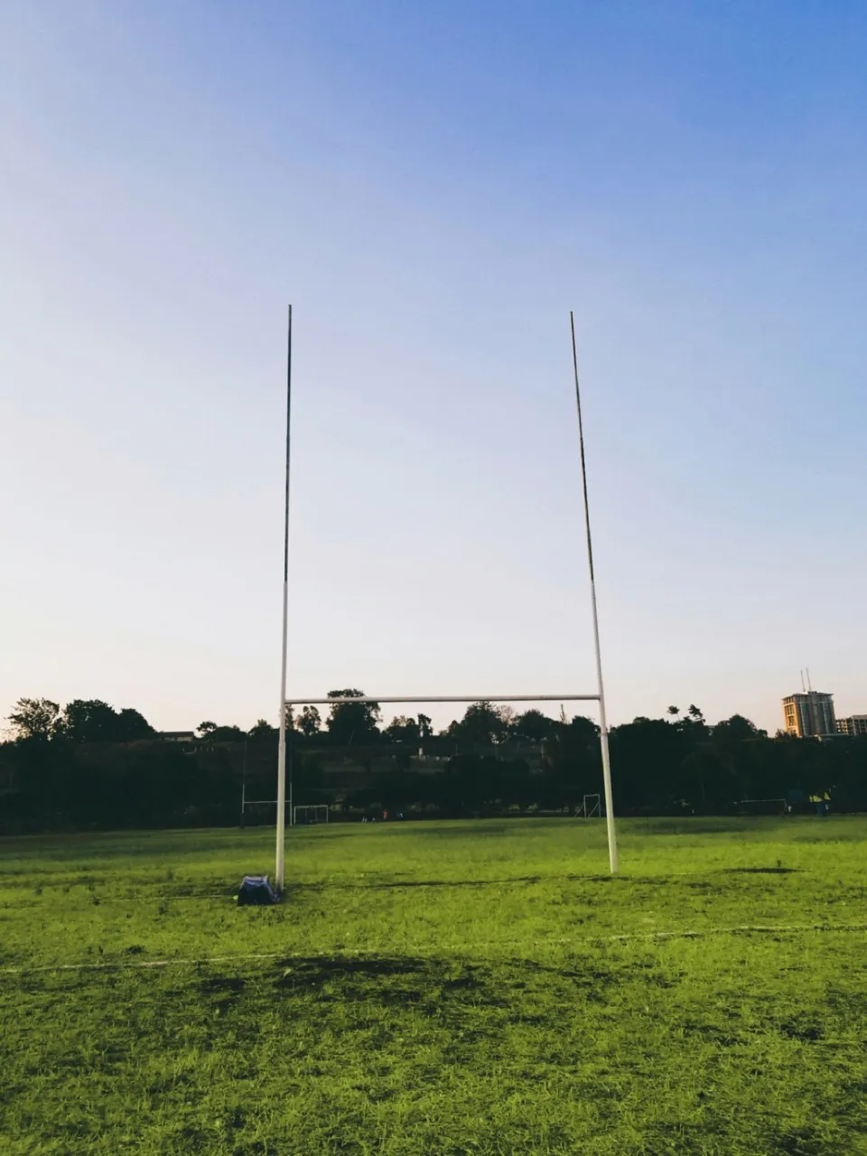 Rugby goalposts on an empty grass pitch at dusk
