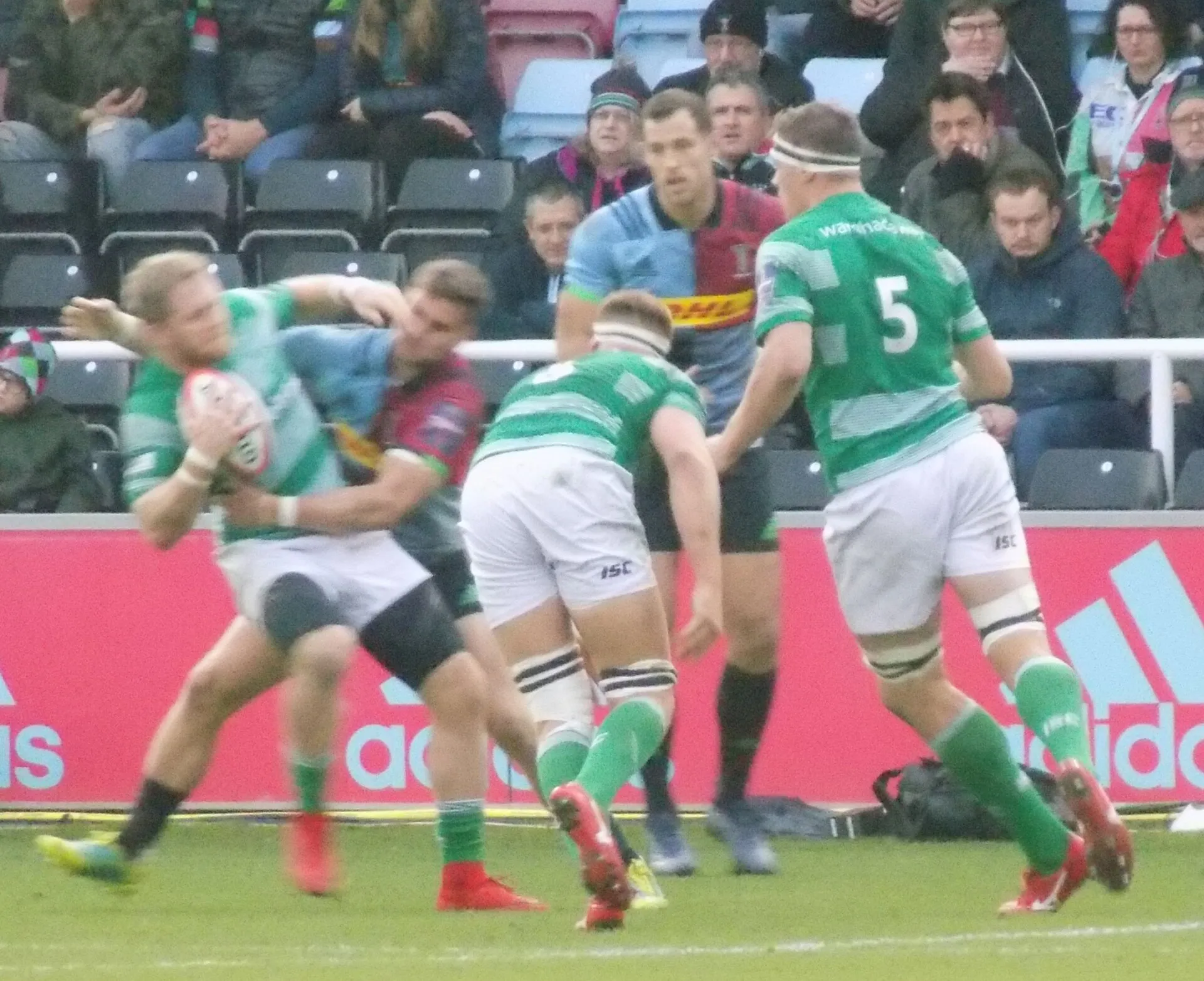 A defender wraps up a ball carrier in a tackle during a rugby union match