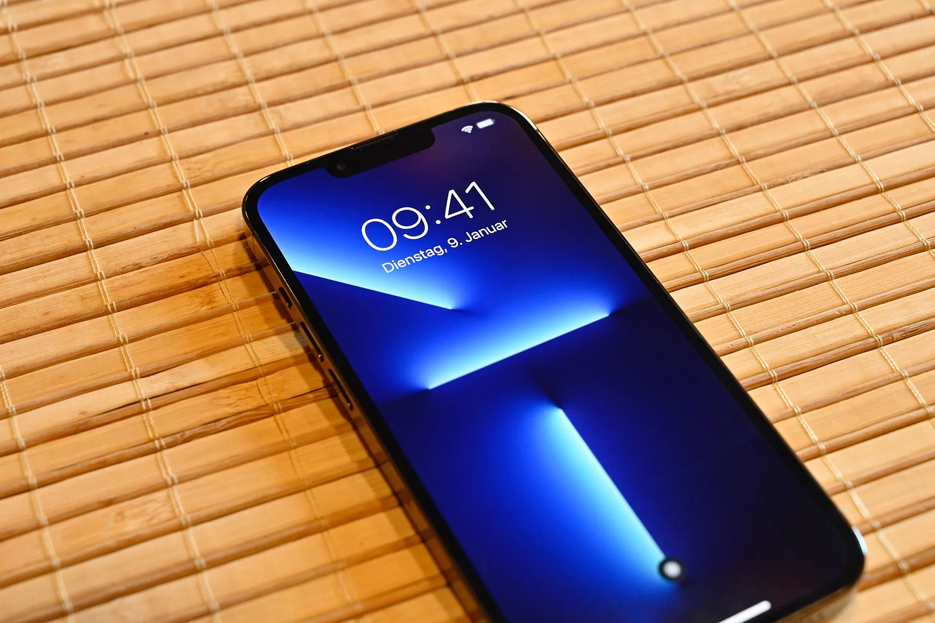 An iPhone lying on a bamboo mat, its lock screen lit up
