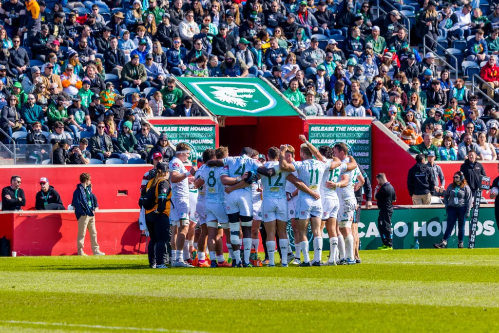 The Chicago Hounds in a team huddle on the pitch in front of a packed home crowd