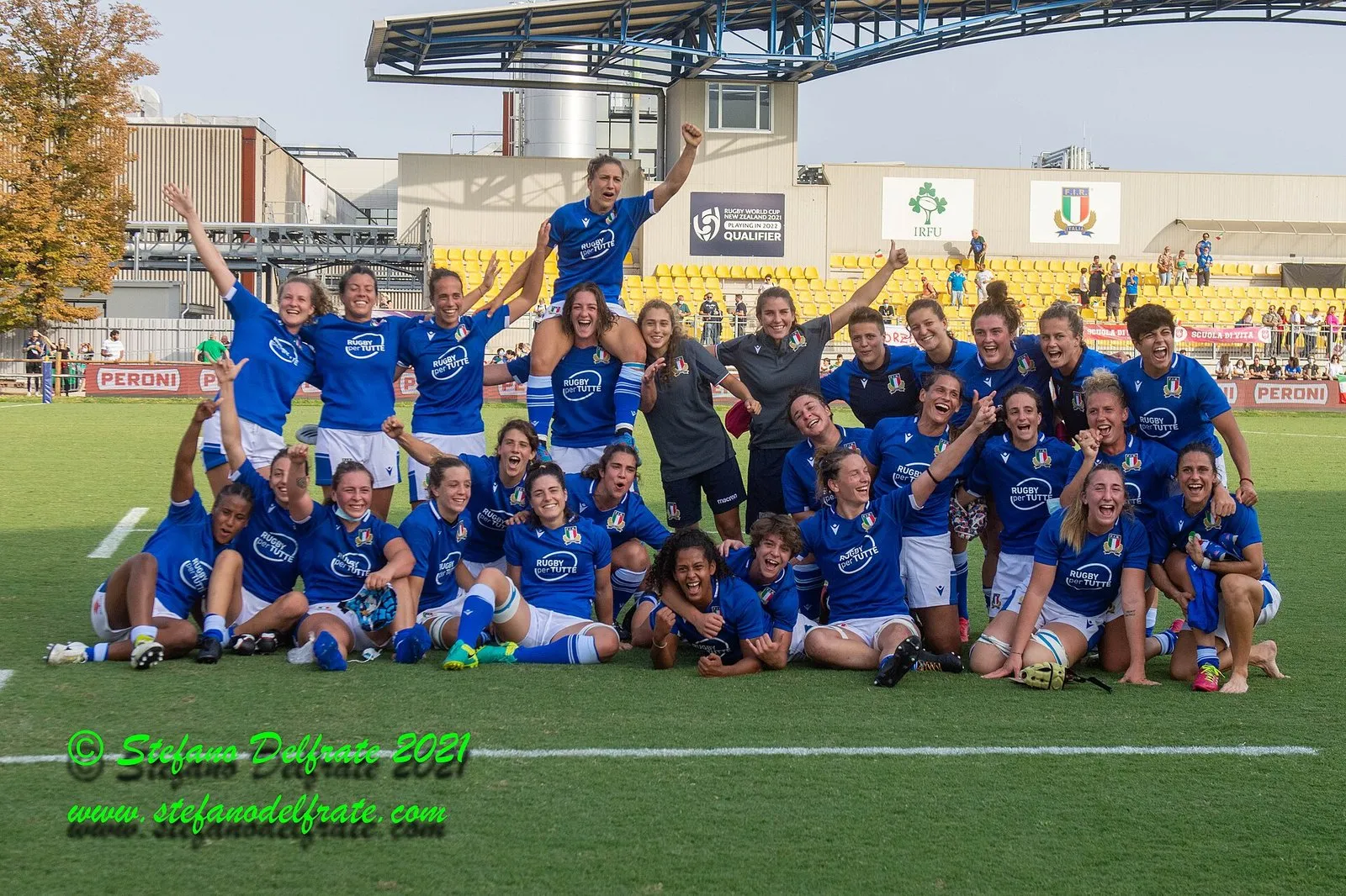 A rugby team celebrates together on the pitch