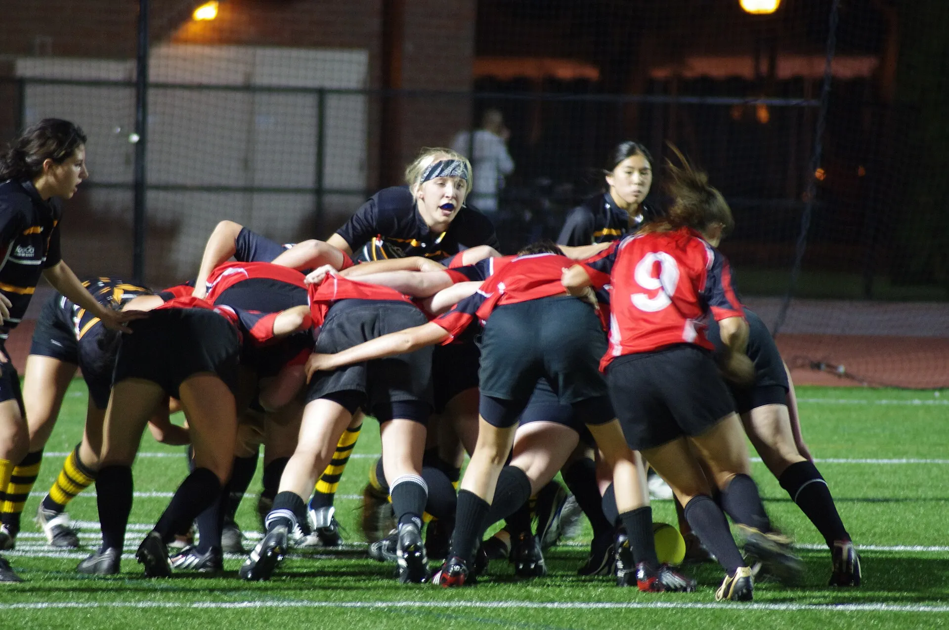Players contest possession under floodlights late in a rugby match