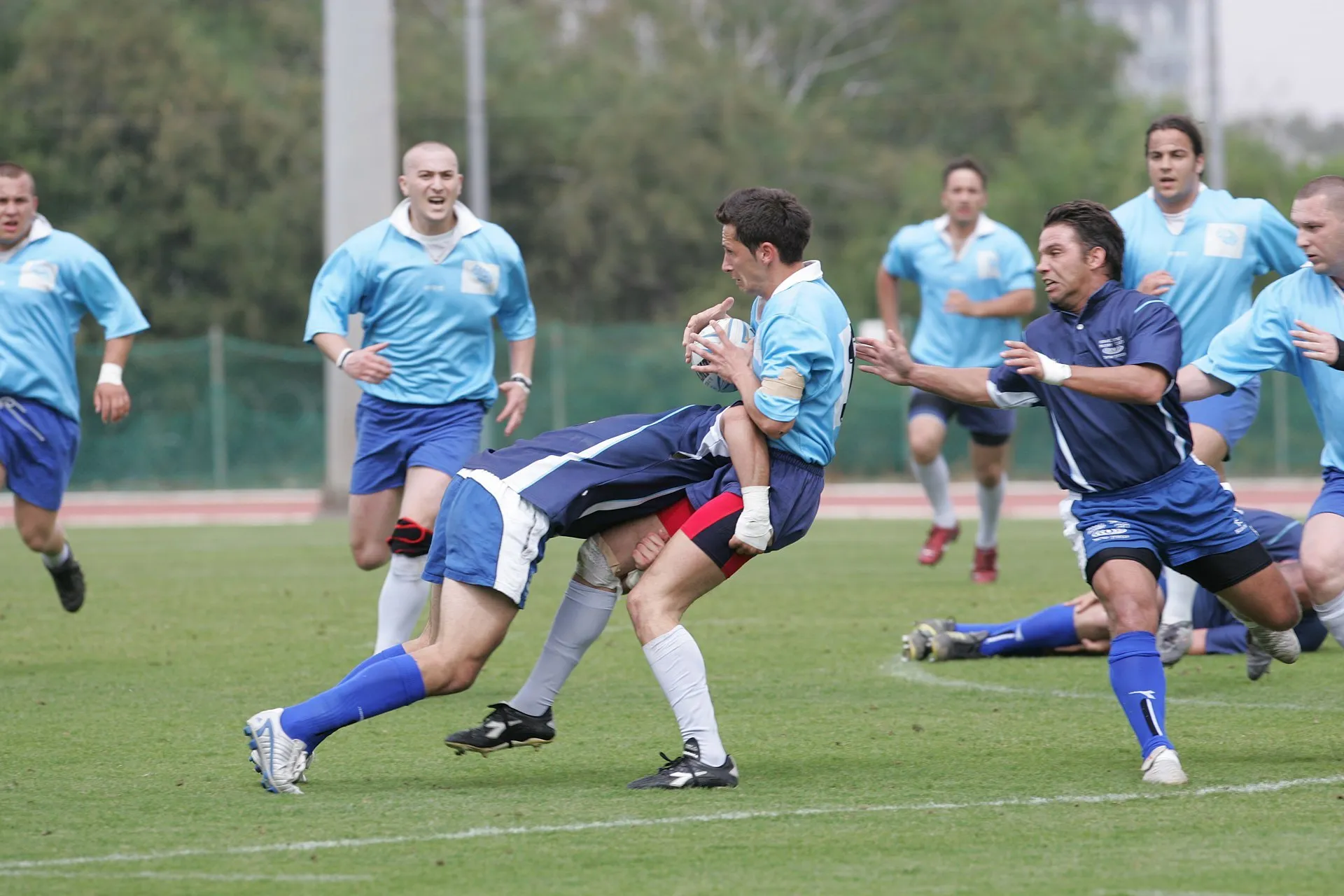 A ball carrier is tackled around the legs during a lower-league rugby international