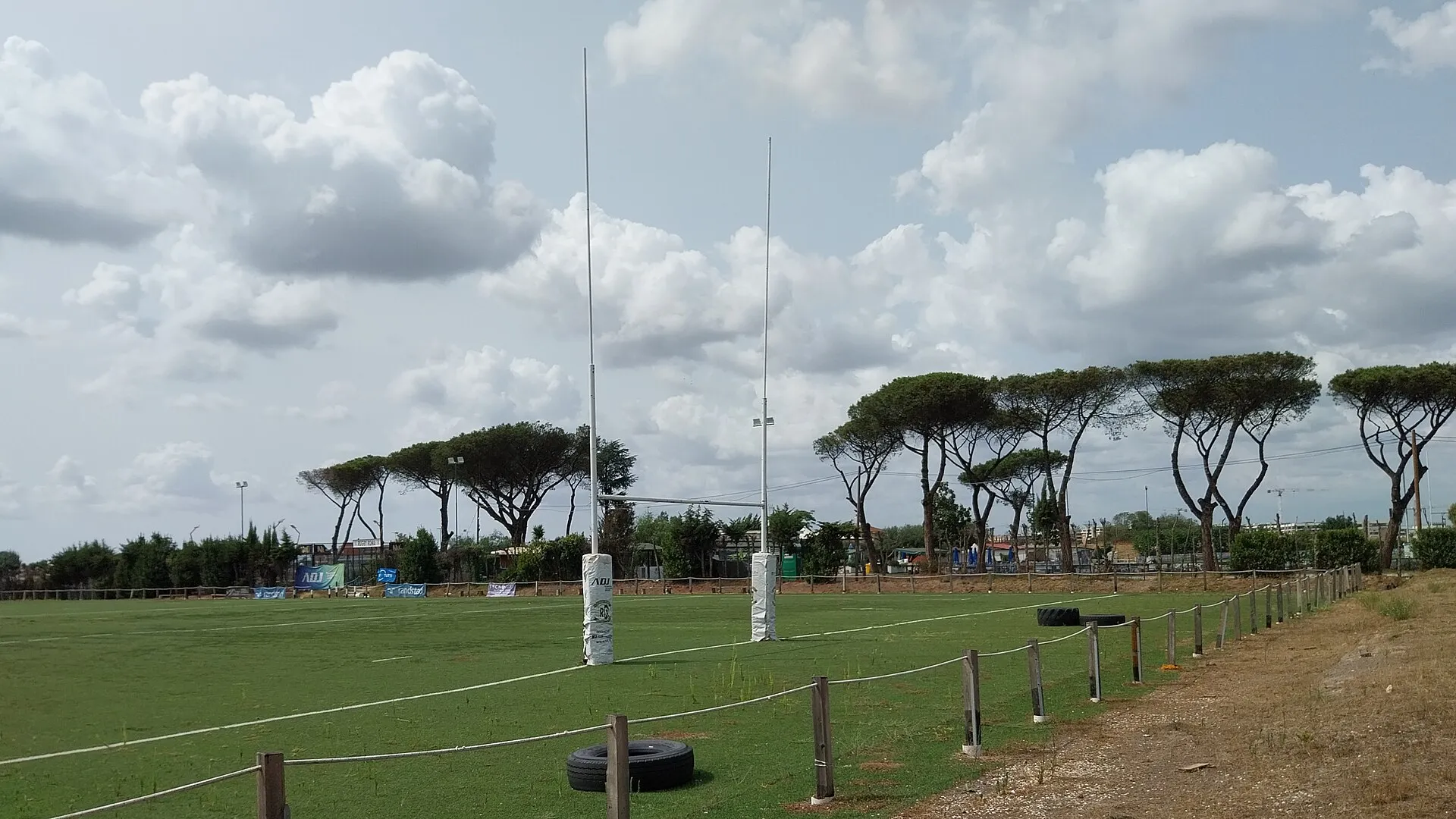 An empty rugby pitch and posts at a club ground on a bright day