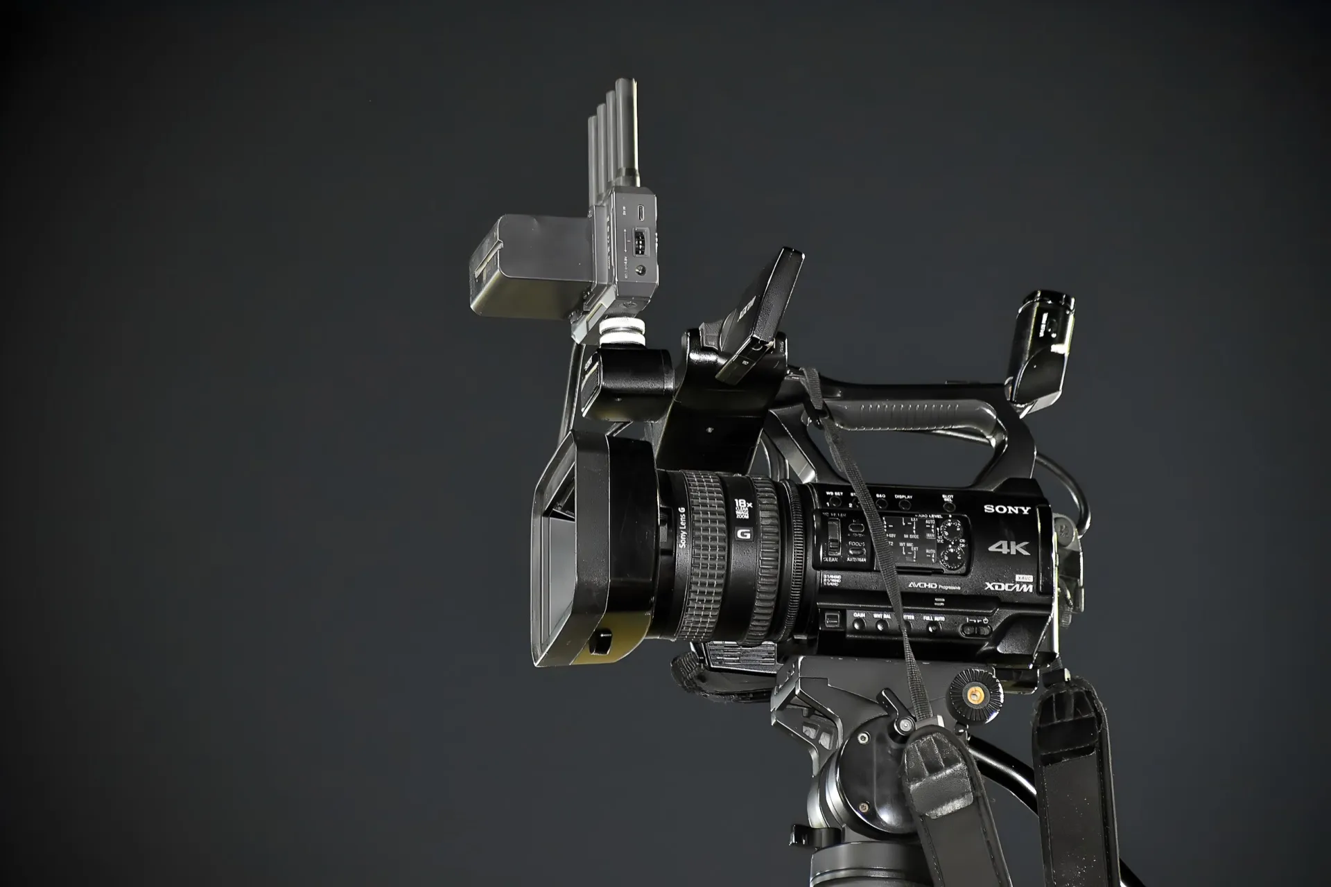 A Sony 4K camcorder mounted on a tripod against a dark grey background
