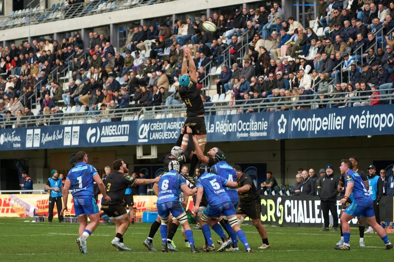 A rugby lineout in a stadium ringed with sponsor advertising boards and a watching crowd