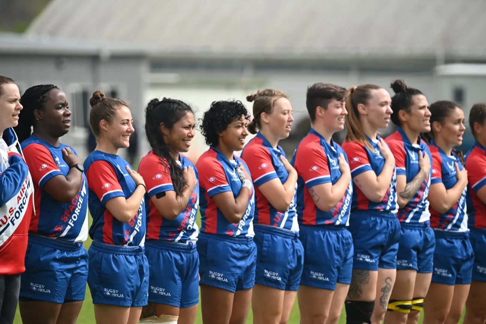 A women's rugby team lined up arm in arm on the pitch after a final