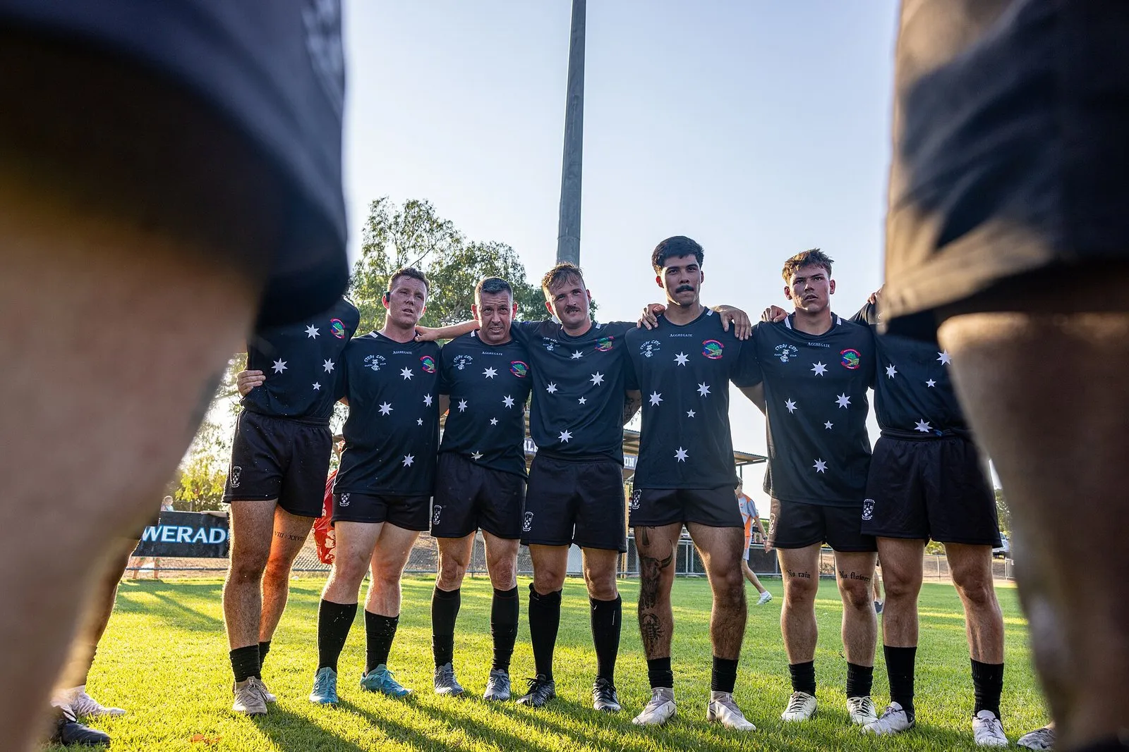 A rugby squad gathers in a huddle for a team talk