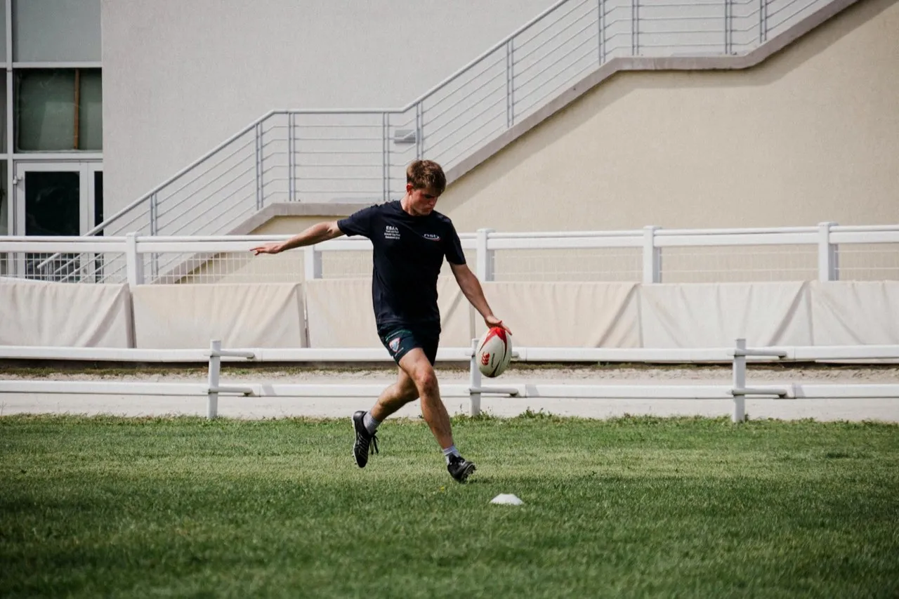 A lone rugby player practising his kicking on a training pitch