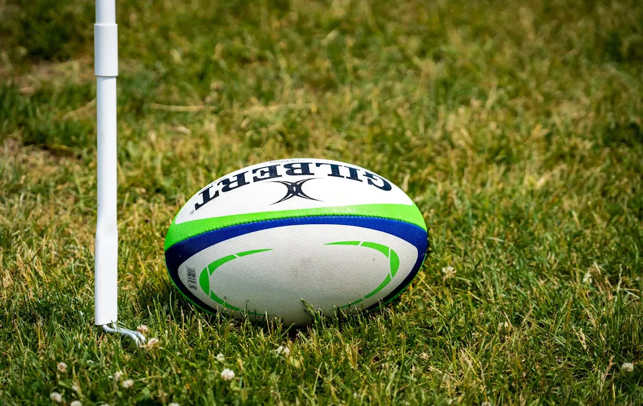 A rugby ball resting beside the corner flag on an empty pitch