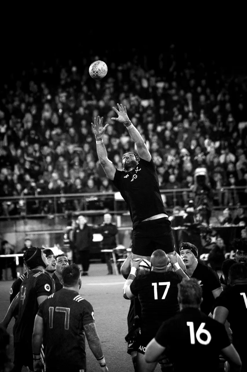 Black-and-white shot of a player leaping to win lineout ball in a packed stadium