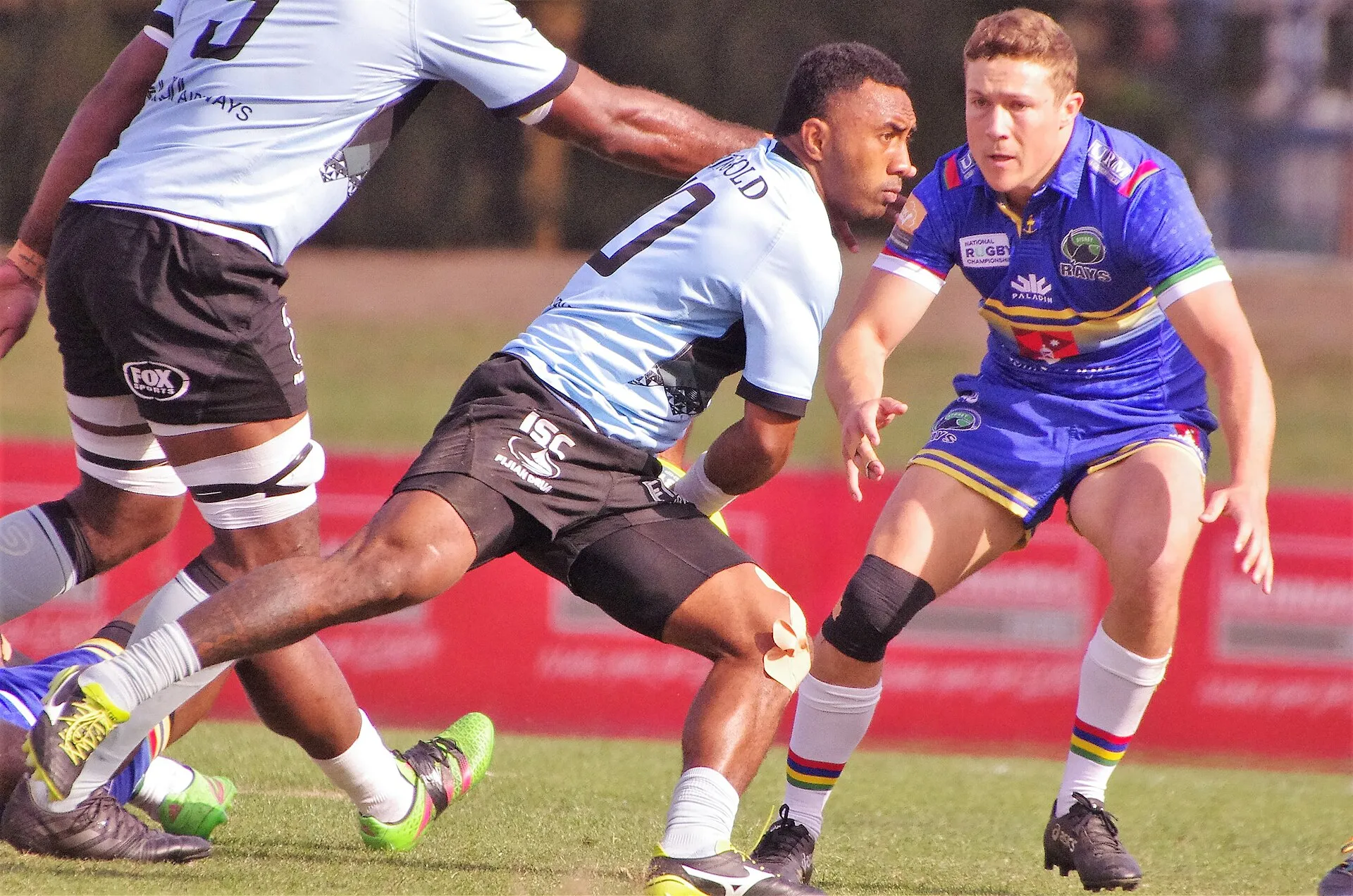 A fly-half releasing a pass as a scrum-half closes in to tackle him