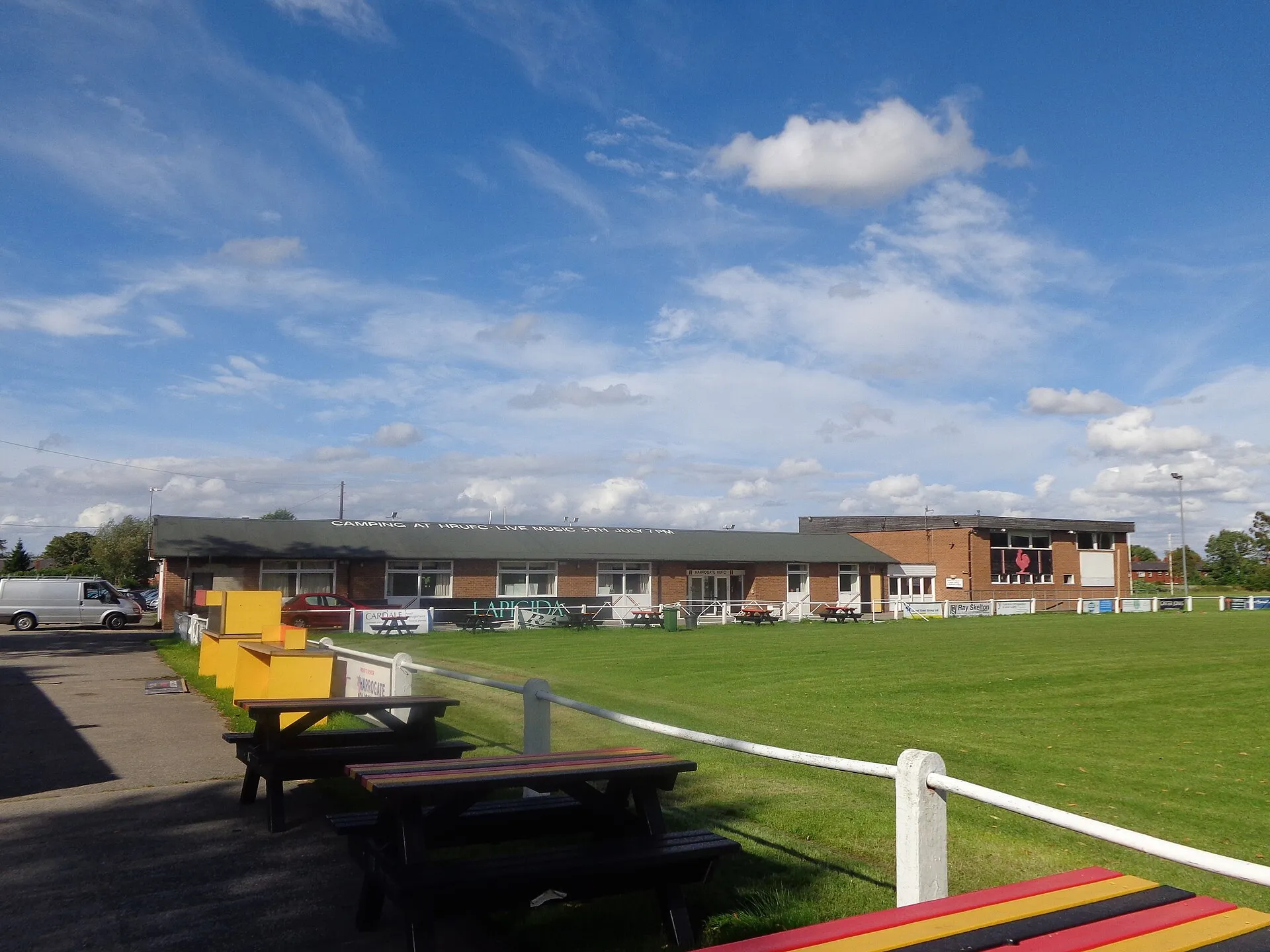 The clubhouse and pitch at an amateur rugby club on a summer afternoon