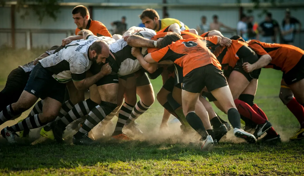 Two amateur packs locked in a scrum in low evening light