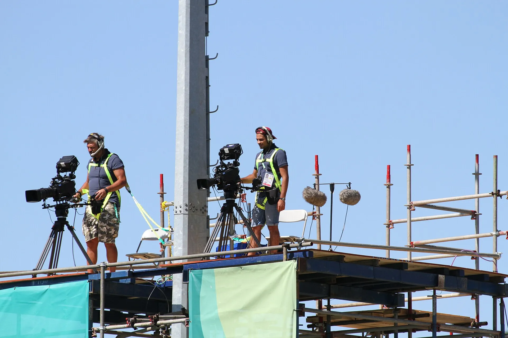 A camera operator filming a rugby match from the side of the pitch