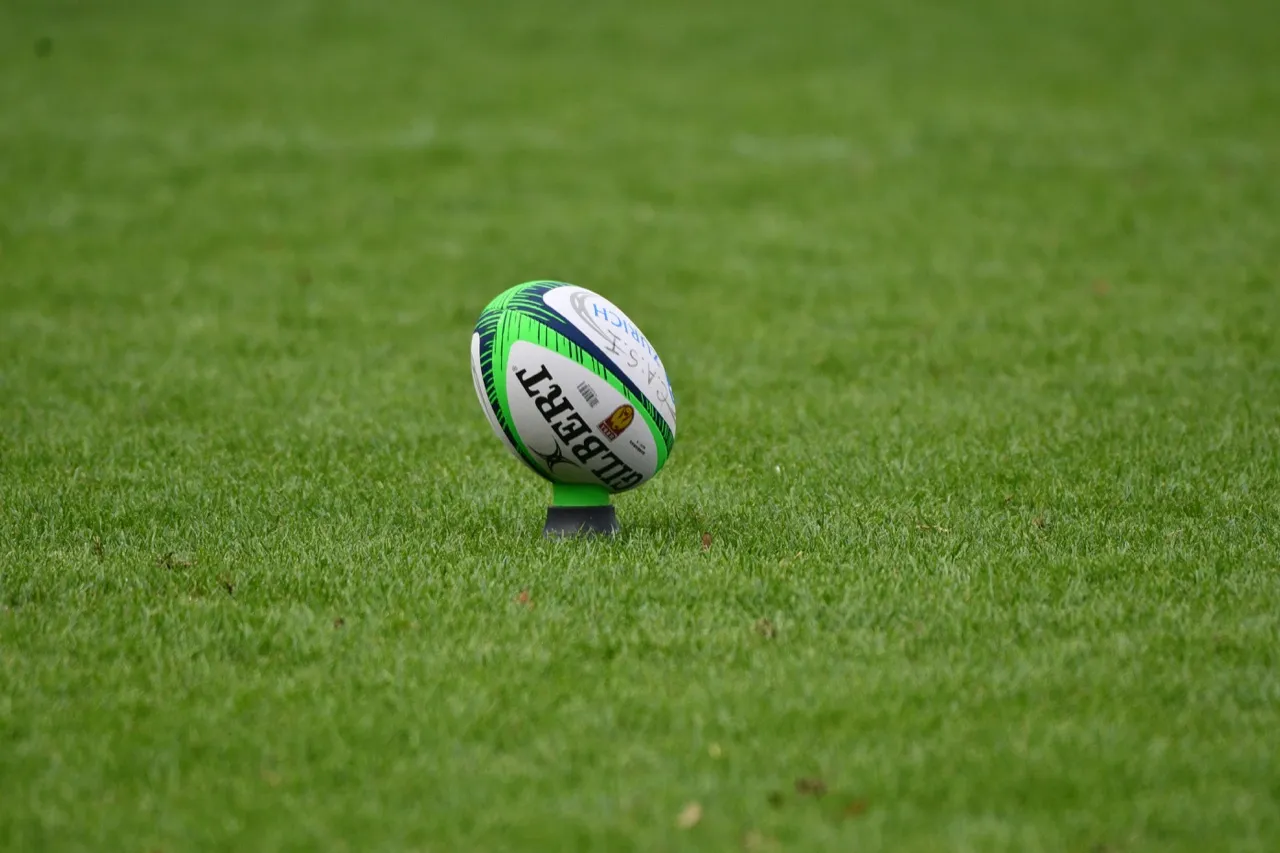 A Gilbert rugby ball on a kicking tee on the pitch, ready for a kick that rugby analysis software can help coaches review