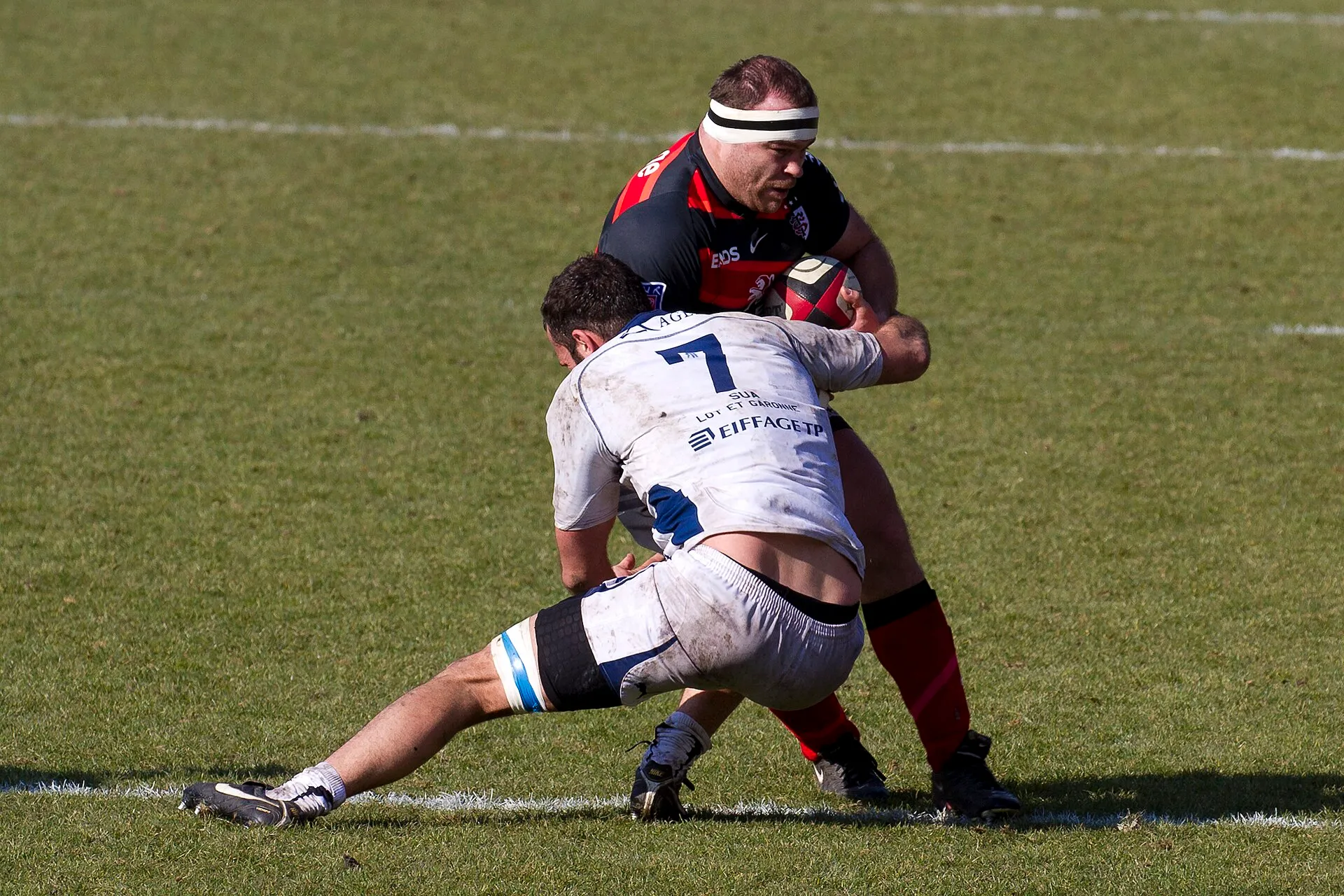 A rugby player wraps up a ball carrier in a tackle