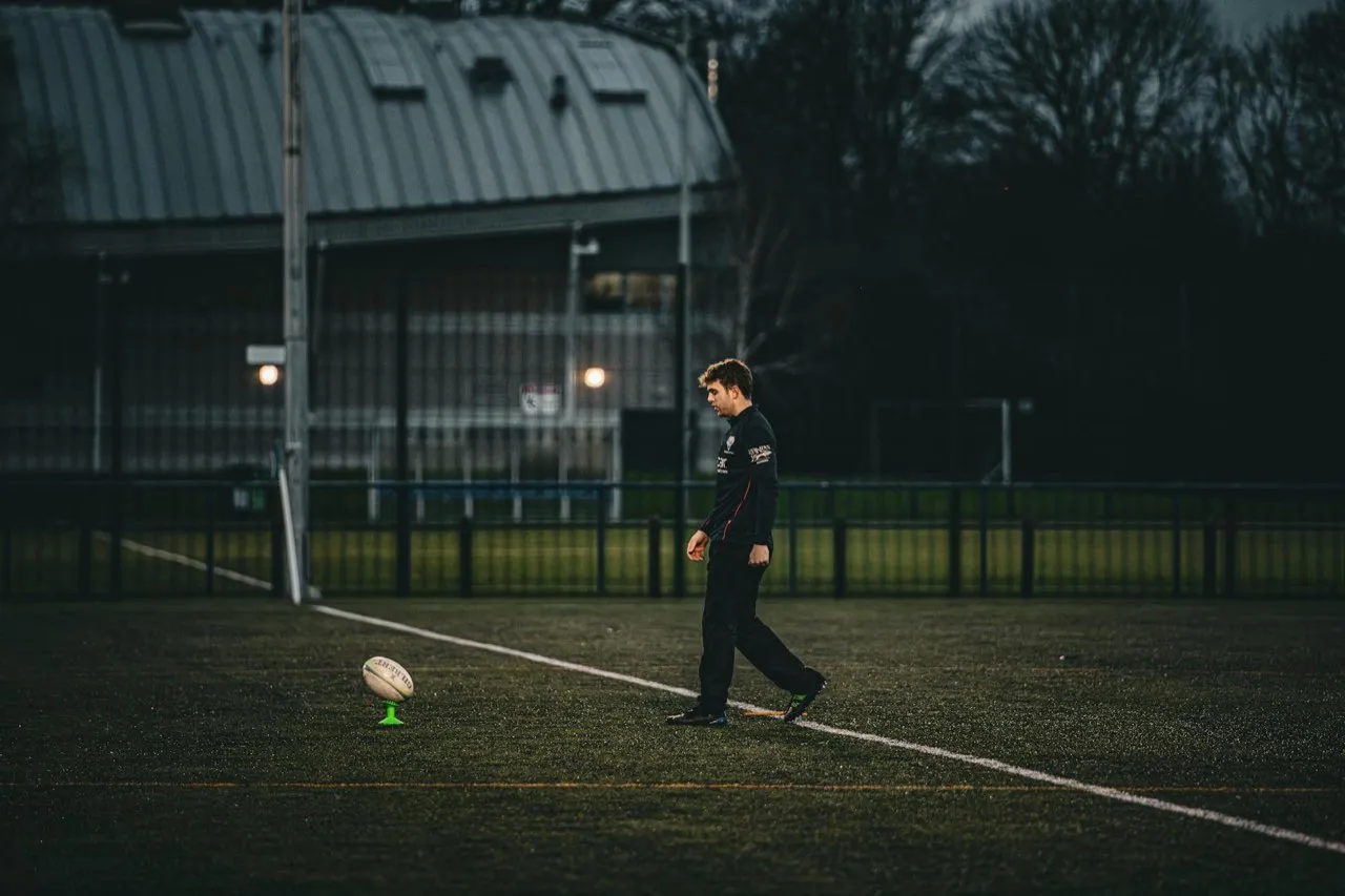 A rugby player lining up a place kick at goal