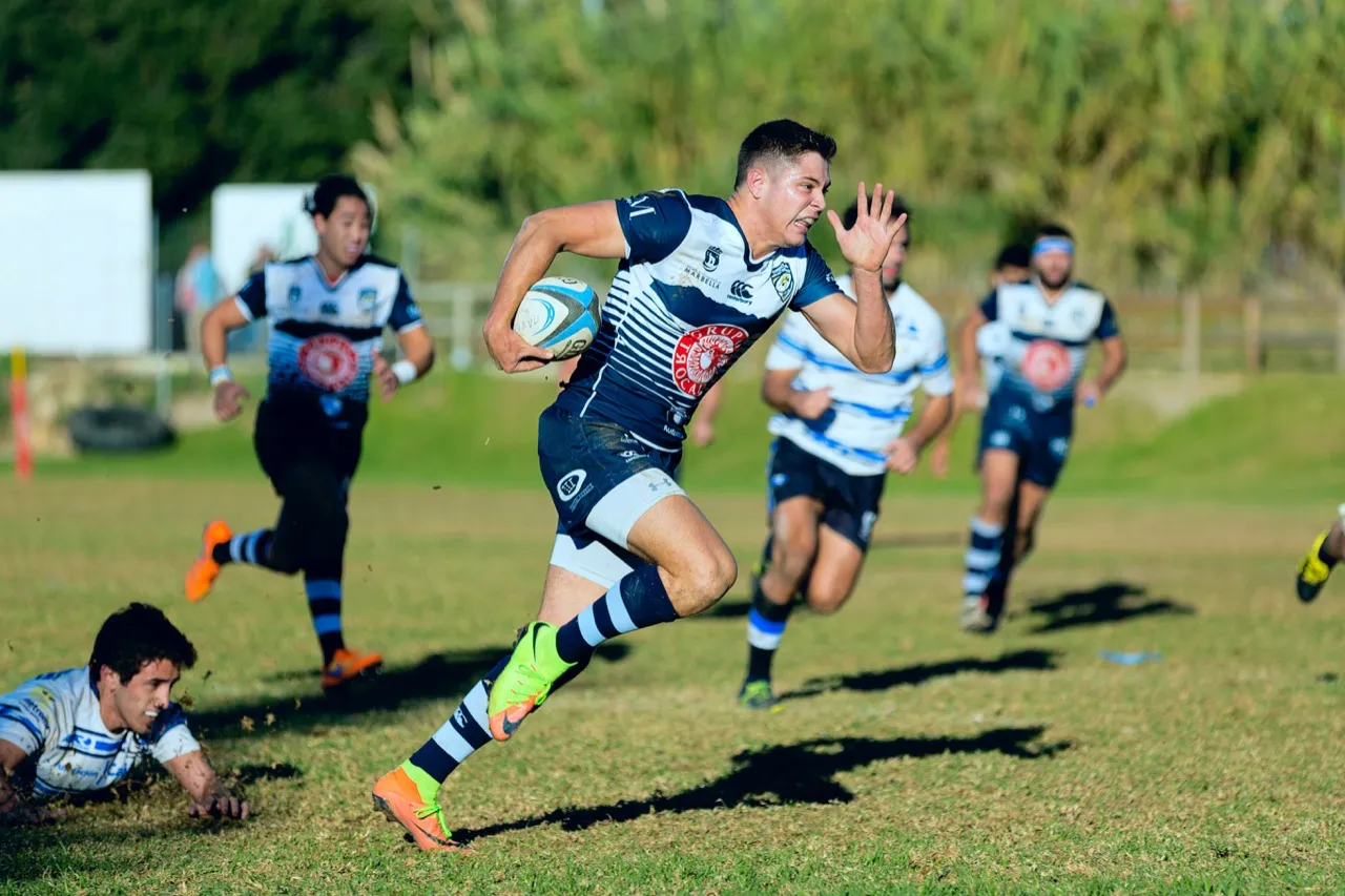 A rugby player breaking away with the ball past defenders during a match